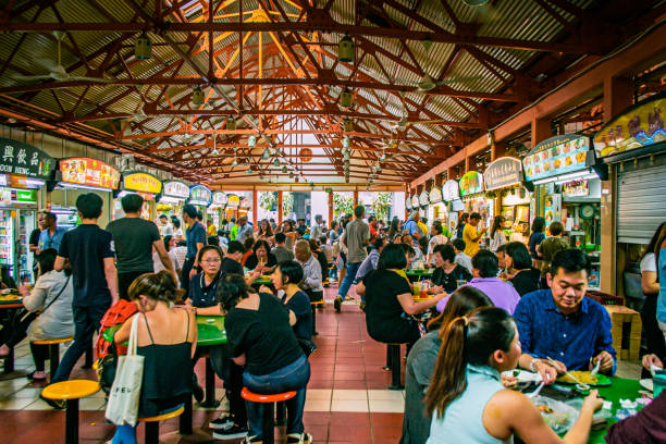 Singapore Hawker Center Locals enjoying food from a Hawker Center in Singapore market trader stock pictures, royalty-free photos & images