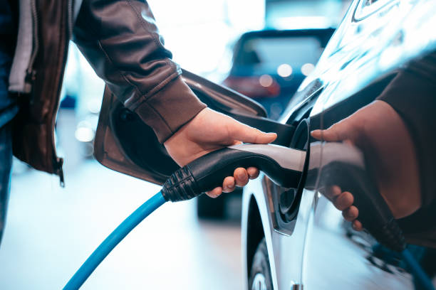Human hand is holding Electric Car Charging connect to Electric car stock photo