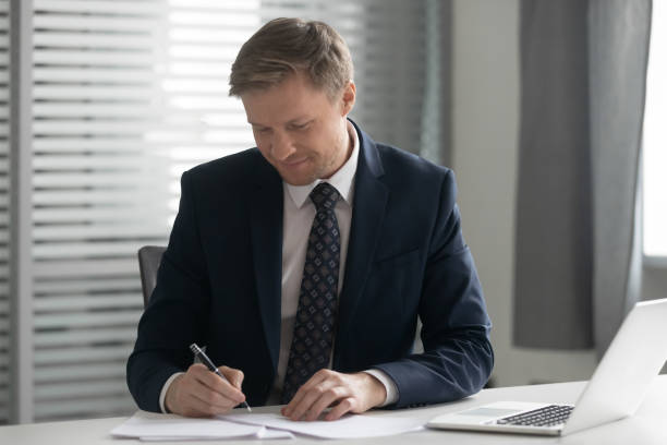 istock Focused businessman put signature on documents in office 1170516721