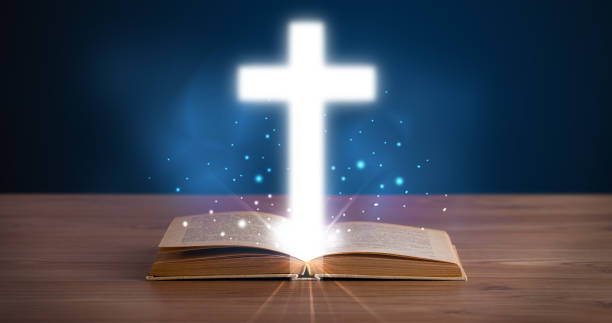 Open holy bible with glowing cross in the middle