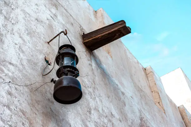 Vintage kerosene lamp on the white wall of a dilapidated building