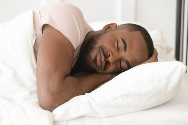 serene calm young black man sleeping well alone in bed - material data sheets imagens e fotografias de stock