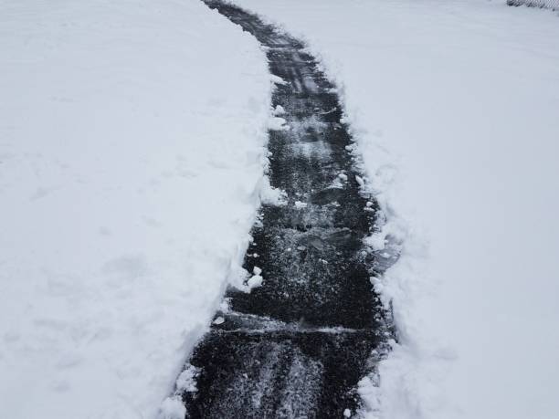 asphalt driveway with white snow and ice shoveling in winter