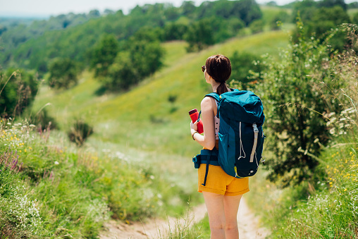 Young female hiker with a thermos and a backpack enjoying on the mountain.