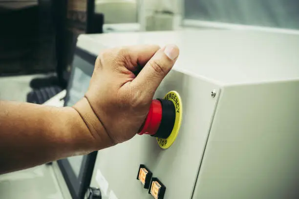 Photo of Male Operator use left hand to push emergency button to stop the machine while accident occur