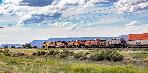 Arizona, USA. May 17, 2019. Freight  BNSF train in Chinle, canyon de Chelly rocks background, sunny spring day