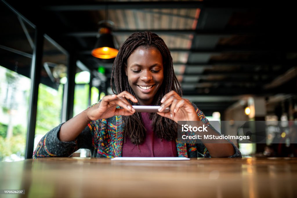 Check remote deposit capture at coffee shop Young African woman making a photo of a check at the bar Bank Deposit Slip Stock Photo
