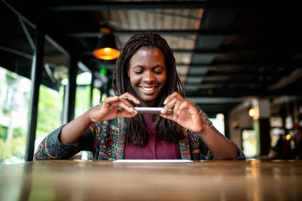 Young African woman making a photo of a check at the bar