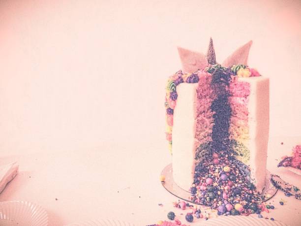 Festive Rainbow Unicorn Cake Pink Background w/Copy Space Festive rainbow unicorn cake sliced revealing brightly colored candy and sprinkles. 21st birthday stock pictures, royalty-free photos & images