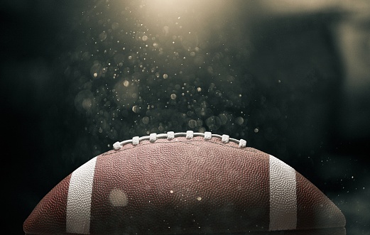 American football ball on black background illuminated