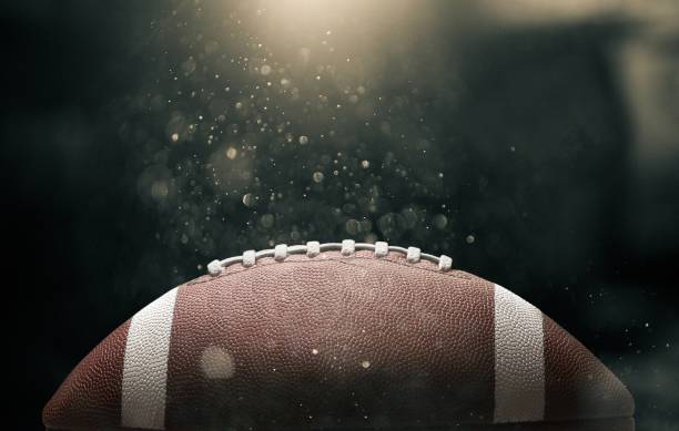 American. American football ball on black background illuminated american football sport stock pictures, royalty-free photos & images