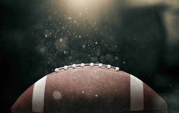 American. American football ball on black background illuminated entertainment equipment stock pictures, royalty-free photos & images