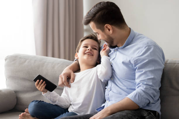 istock Loving father hugging little son, having fun together, using phone 1170534185