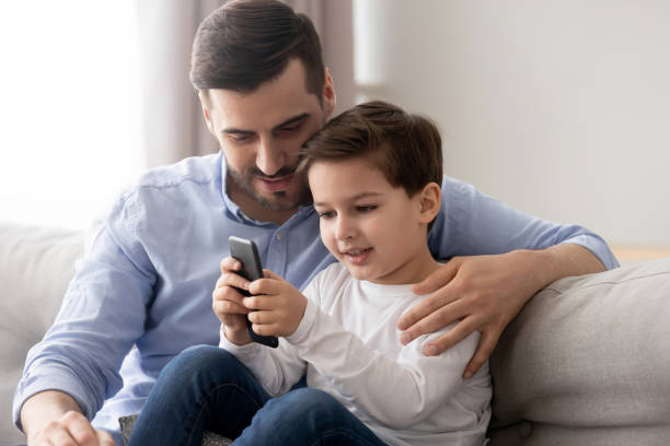 istock Caring father hugging, teaching little son to use phone 1170534191