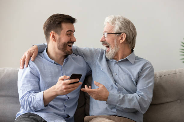 istock Happy old father and son having fun, using phone together 1170534243