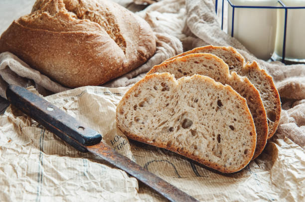 A beautiful loaf of sourdough bread from white wheat on a plate on a linen edge. Homemade pastries stock photo