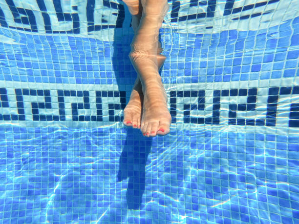 istock Feet, with nails painted in red, submerged in pool water 1170536340