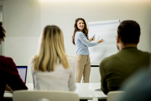 Rear view of a businesswoman standing on a seminar in board room and talking to public speaker. Copy space.