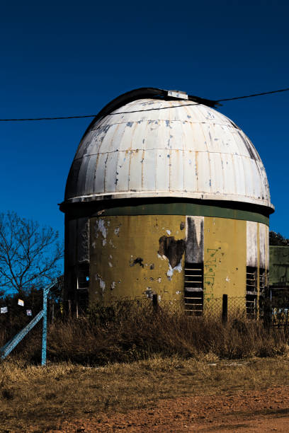 Poços de caldas, minas gerais, BRAZIL - Abandoned astronomical observatory with peeling yellow walls and white dome under a cloudless sky.