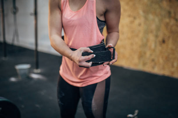 mujer poniéndose cinturón para el entrenamiento de levantamiento muerto - body building gym human muscle effort fotografías e imágenes de stock