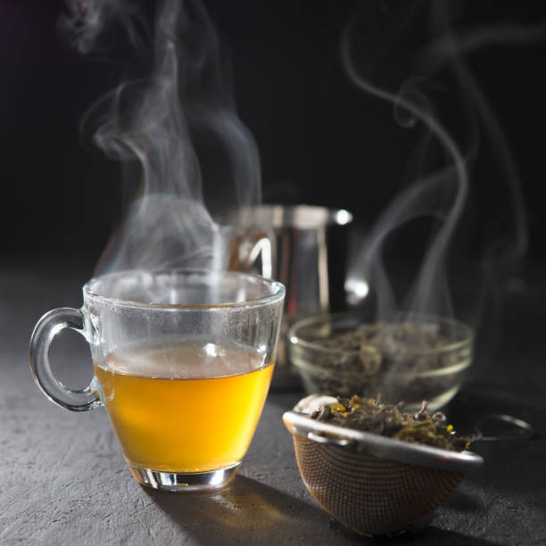 istock Process brewing tea,tea ceremony,Cup of freshly brewed yellow or green herb tea,warm soft light, dark mood.Hot water is poured from the kettle into a cup with tea leaves. 1170552740