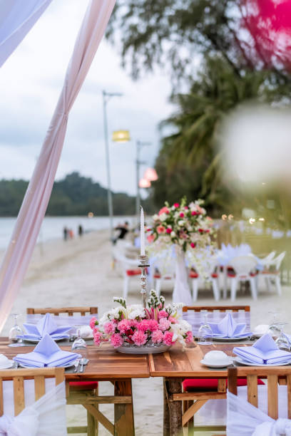 istock Romantic dinning table on the beach . Table setting at a luxury wedding and Beautiful flowers on the table. 1170557802
