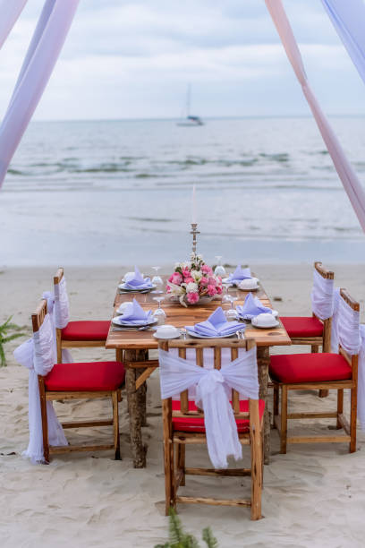 istock Romantic dinning table on the beach . Table setting at a luxury wedding and Beautiful flowers on the table. 1170557819