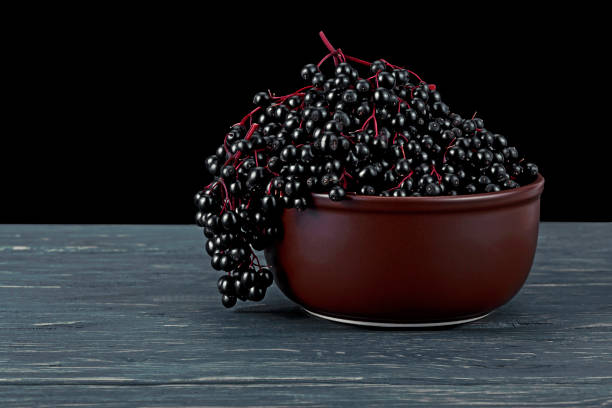 istock Black elderberries in clay bowl on rustic wooden table. Sambucus nigra. 1170561624
