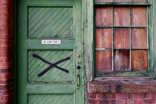 Medium shot of green door and window of abandoned factory