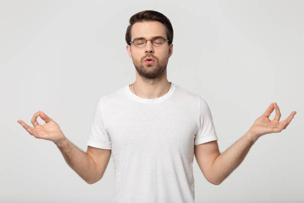 istock Young man in glasses doing breathe exercises isolated on grey 1170563979