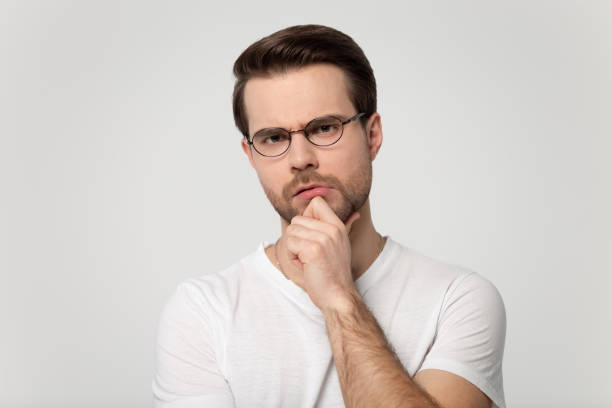 istock Frowning man holding hand on chin feels distrustful studio shot 1170563994