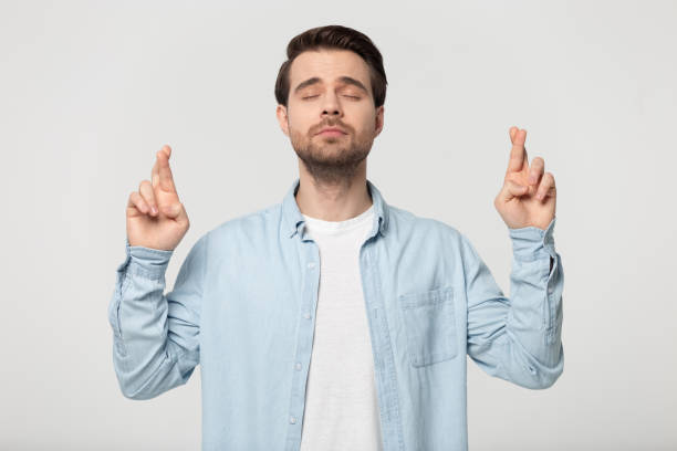 istock Guy with closed eyes crossing fingers posing isolated on grey 1170564045