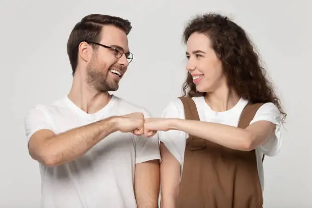 Photo of Girl guy smiling gives fist bump pose isolated on grey