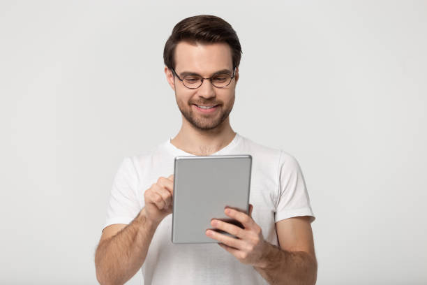 istock Millennial guy in glasses using tablet isolated on grey background 1170564156