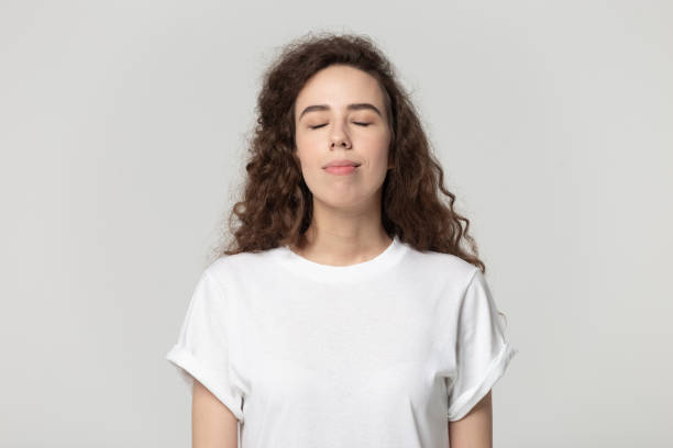 istock Woman closed eyes enjoy fresh air pose isolated on grey 1170566469