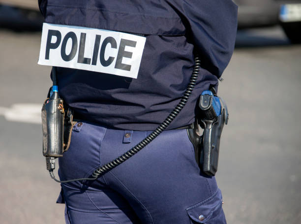 銃とトランシーバを持つ「police」の碑文を持つ警官の背中。 - paris france audio ストックフォトと画像