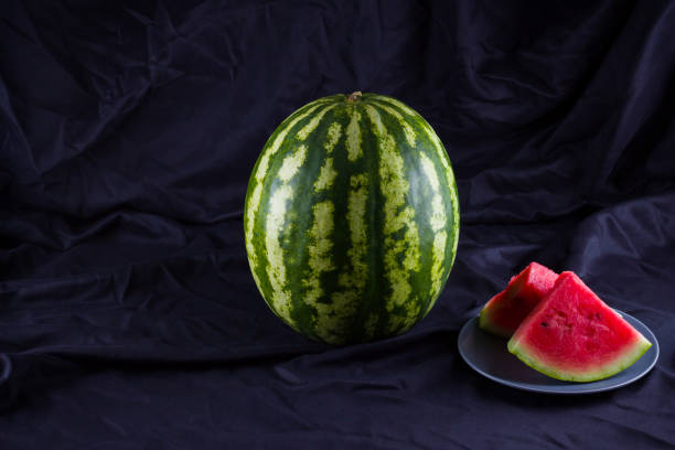 Watermelon on black cloth. Whole watermelon on dark background. Healthy food for vegan. Copy space
