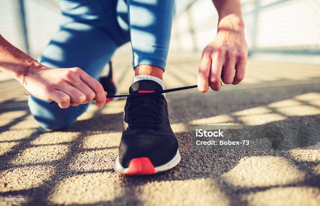 Tying sports shoes. Sport, exercise, fitness, workout Tying sports shoes. Woman getting ready for athletic and fitness training outdoors. Sport, exercise, fitness, workout. Healthy lifestyle Active Lifestyle Stock Photo