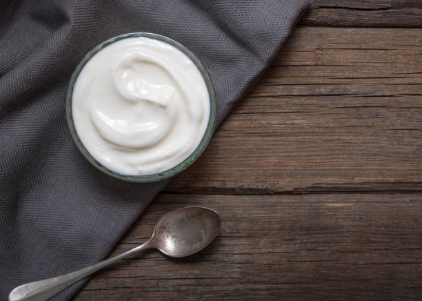 istock White yogurt in glass bowl on old wooden desk with old rustic spoon. 1170575849