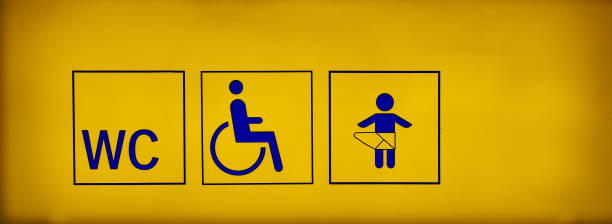carteles de baños públicos con un símbolo accesible para minusválidos y vestuario para bebés en letrero de neón amarillo. - bath and body fotografías e imágenes de stock
