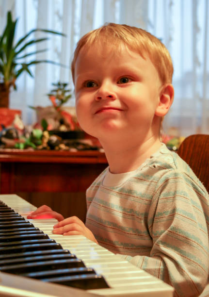 istock Little blonde boy playing piano, side view, blurred and grain effect. 1170582699