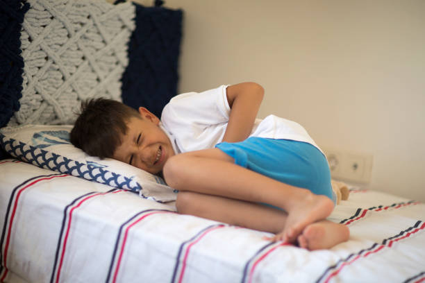 Young boy lying in bed with stomachache Young boy lying in bed with stomachache diarrhea photos stock pictures, royalty-free photos & images