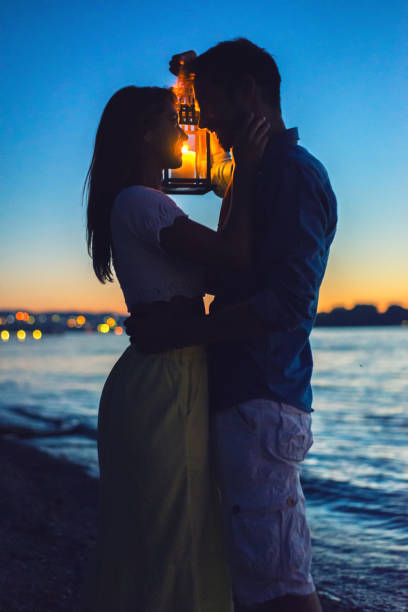 Young romantic couple in love hugging on the beach at summer night.