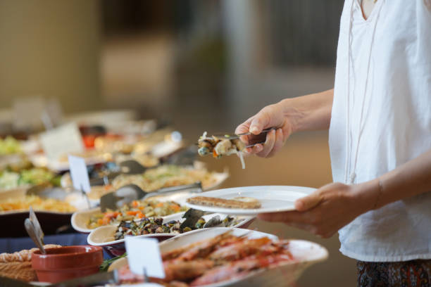 femme prenant la nourriture d'une ligne de buffet - buffet repas photos et images de collection