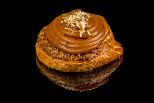 istock bun with nuts and caramel on black glass with reflection 1170596386
