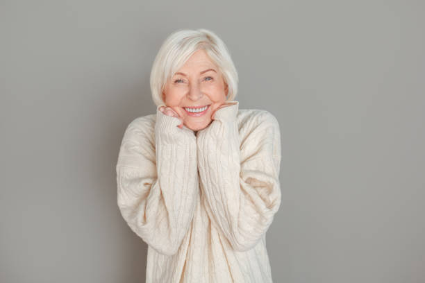 istock Senior woman in sweater studio isolated on grey wall touching face joyful 1170598420