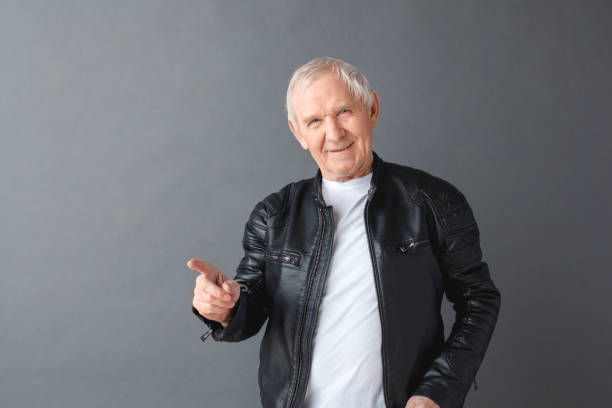 istock Senior man in leather jacket standing isolated on gray pointing preaching looking camera sly 1170598703