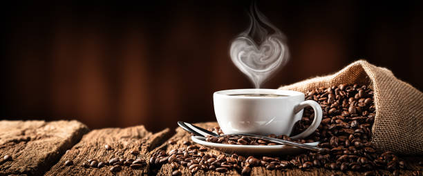 Hot Coffee With Heart Shaped Steam White Cup Of Hot Coffee With Heart Shaped Steam On Old Weathered Table With Burlap Sack And Beans cappuccino photos stock pictures, royalty-free photos & images