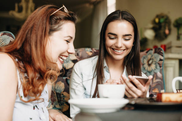 istock Charming caucasian brunette showing something to her plus size girlfriend on a smartphone while laughing in a cafe. 1170616204