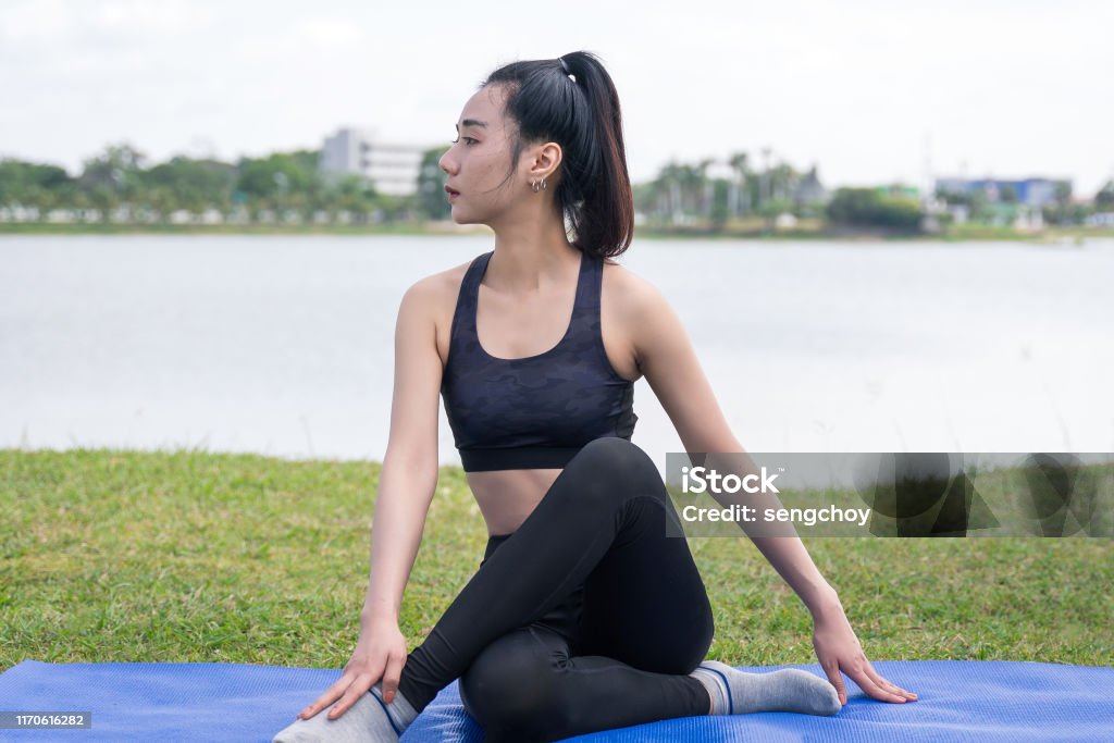 duisternis registreren Gooey Slim Beautiful Women Practices Yoga Poses On The Mat Beside A Lake At The  Outdoor Park With Green Grass Background Yoga And Life Health Concept With  Copy And Paste Space Stock Photo -